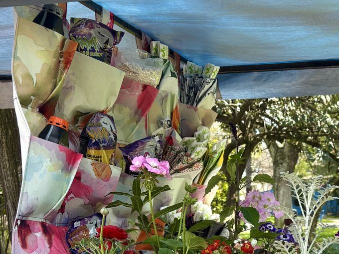 Jardín vertical sublimado con estampa floral colgado en el puesto de la feria, con plantas florecidas delante