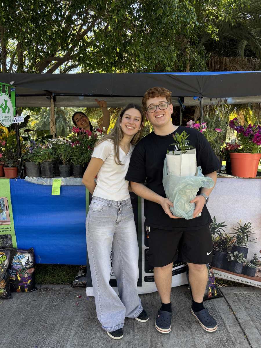 Dos clientes sonrientes con su planta en el puesto de El Parque Macetas en la feria