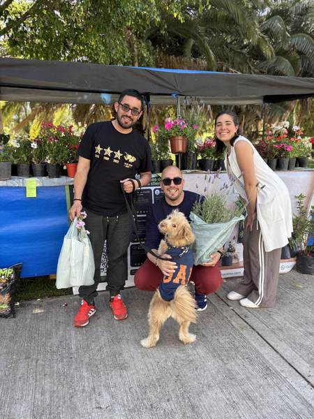 Clientes con su perro y sus plantas frente al puesto de El Parque Macetas en la feria